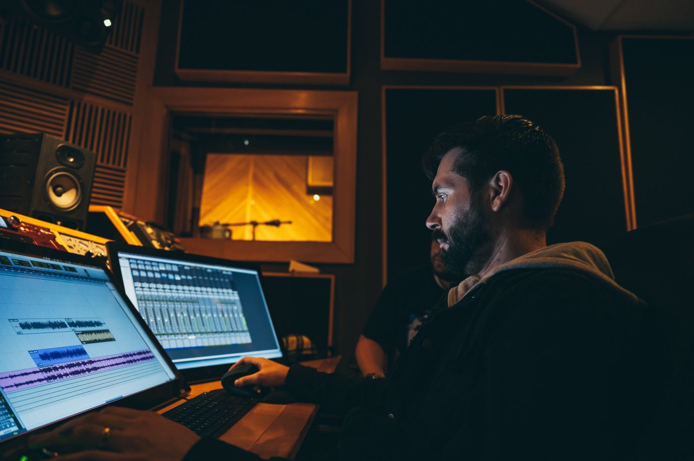 A sound engineer working in music software on two screens
